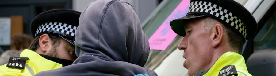 Photo of police arresting a young man in a hoodie