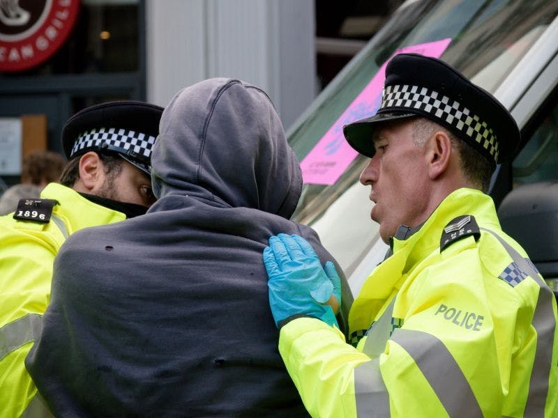 Photo of police arresting a young man in a hoodie