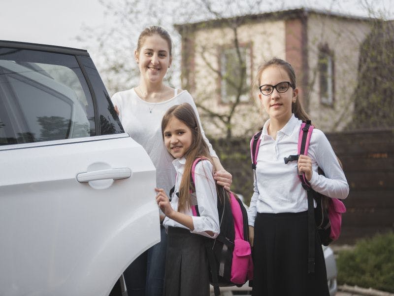 Photo of a mum taking two young girls to school in a car