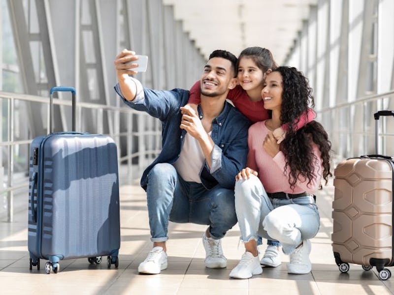 Photo of a young family taking a selfie at the airport