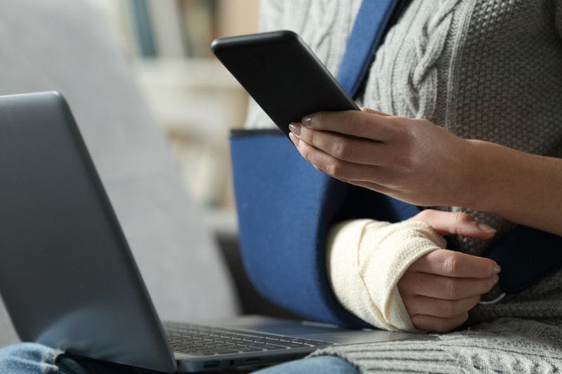 Photo of woman with arm injury looking at phone