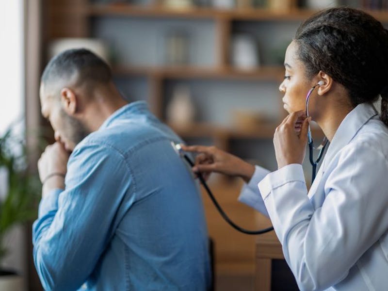 Doctor using stethoscope on mans back