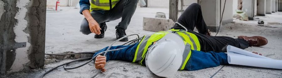 Injured worker in safety gear laid on floor