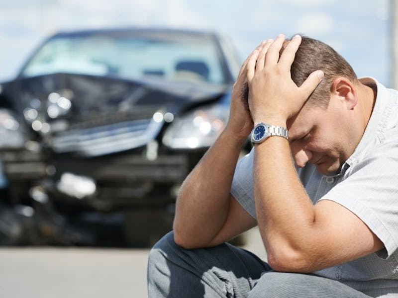 man sitting in front of damaged car