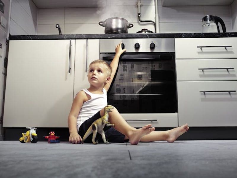 child playing in front of a cooker with a pan on it