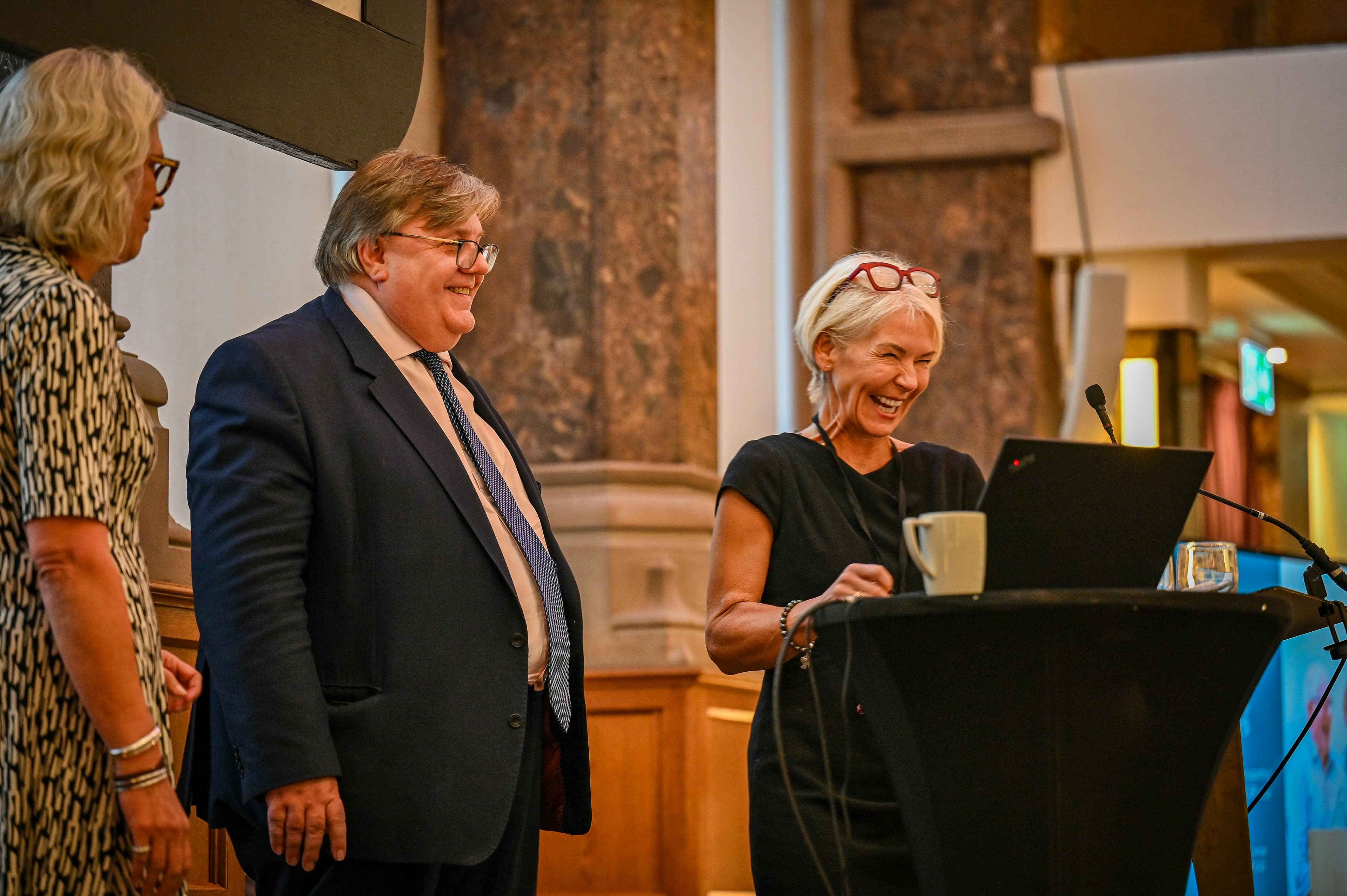 Three people at lectern smiling